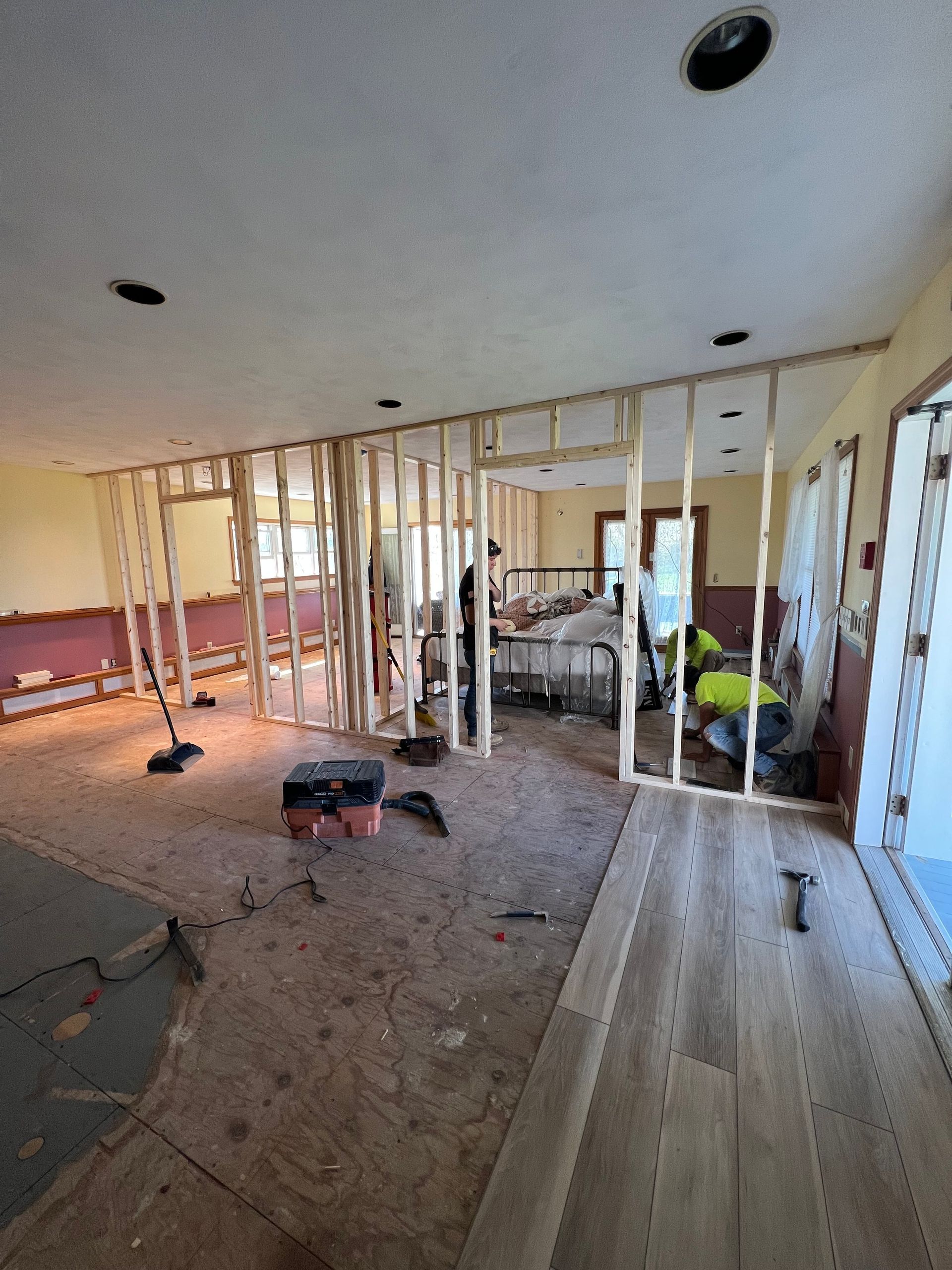 Interior renovation: wooden wall framing in a room with hardwood flooring and debris.