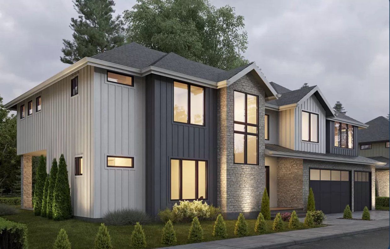 Modern two-story house with gray, white, and stone exterior. Windows and two-car garage. Overcast sky.
