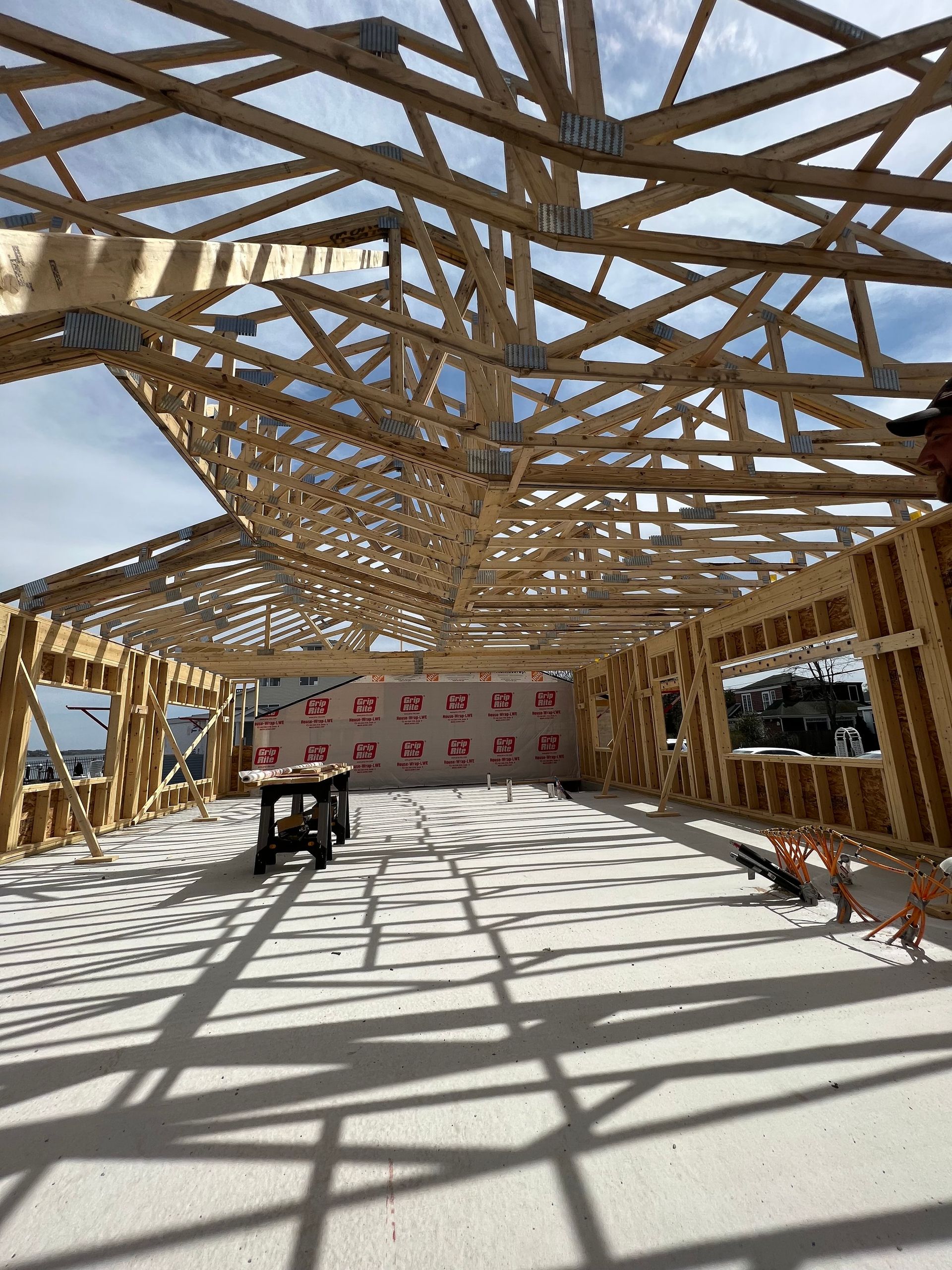Wooden frame of a building under construction, with roof trusses and wall studs visible.