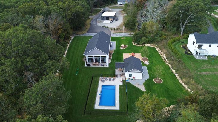 Two-story light gray house with white trim, porch, and two-car garage under a cloudy sky.