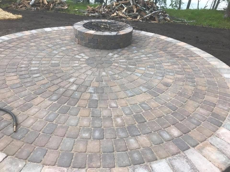 Circular brick patio with a stone fire pit in the center outdoors