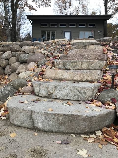 Stone steps leading up to a house with a flat roof. Autumn leaves scattered on the ground.