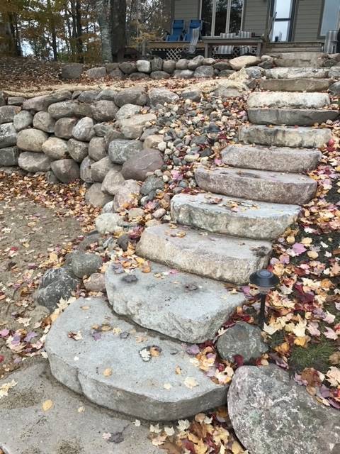Stone steps leading up a hillside, surrounded by rocks and fallen leaves.