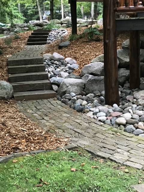 Stone steps and pathway leading up a hillside, surrounded by rocks and mulch.