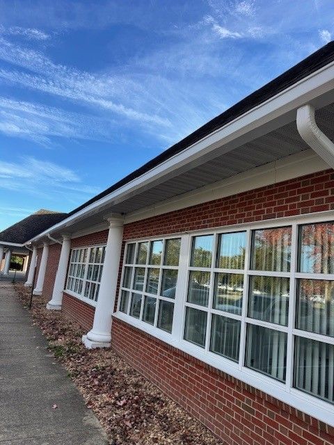 Brick building exterior with white-framed windows and a covered walkway along the side