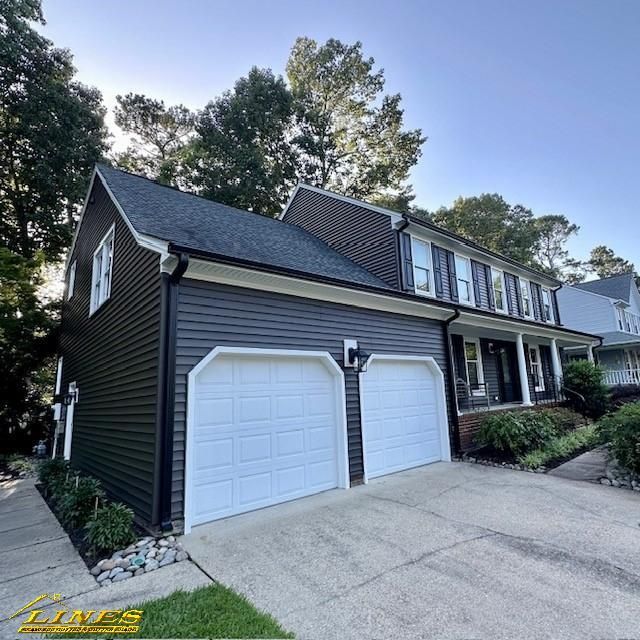 Dark gray house with white garage doors and black shutters.