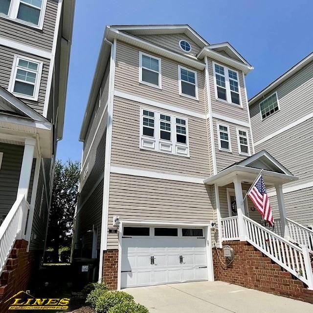 Three-story townhouse with beige siding, white garage door, brick accents, and an American flag.