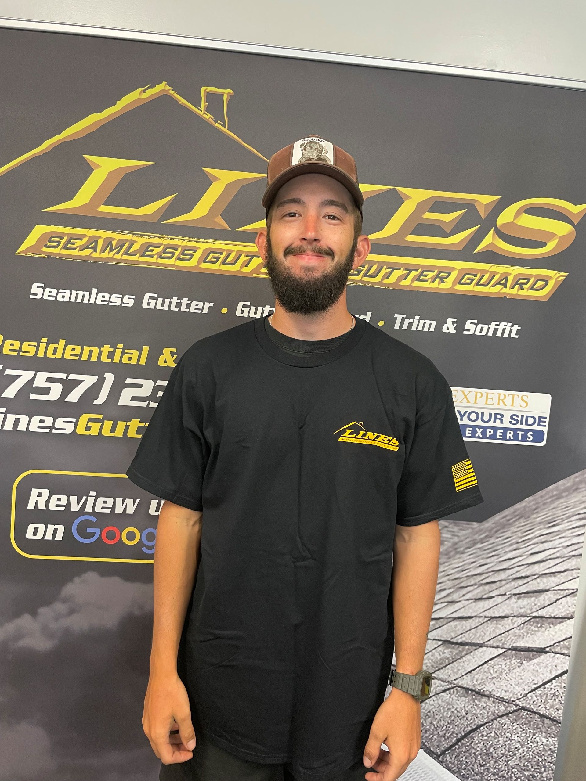 Man in a black shirt and cap stands in front of a company banner for