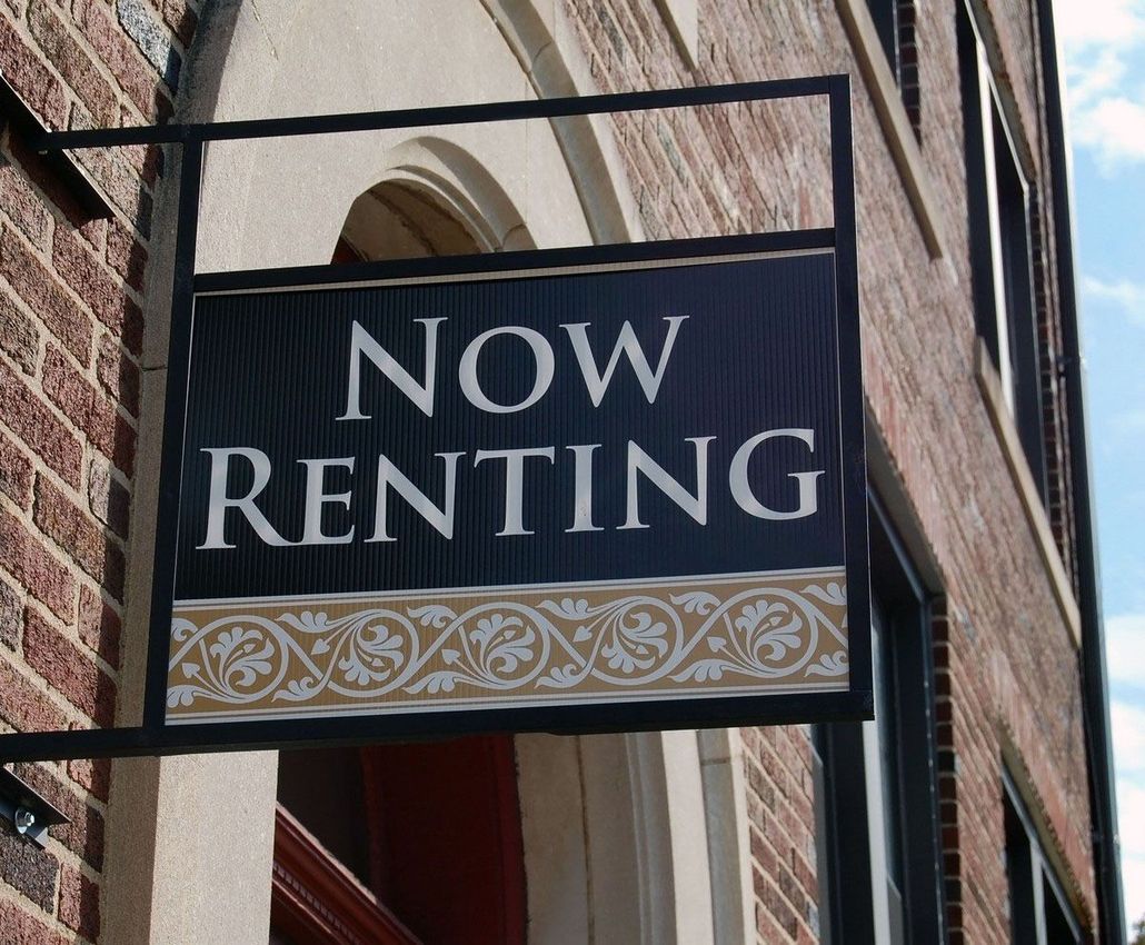 Now Renting sign on a brick building exterior