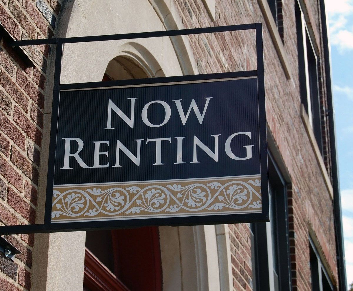 Now Renting sign on a brick building exterior