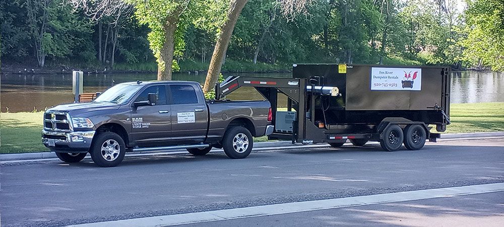 a truck is pulling a dumpster on a trailer