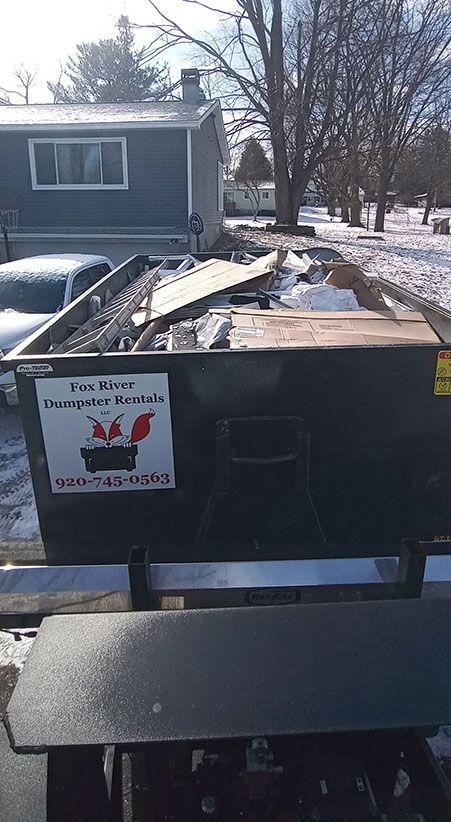 a dumpster is sitting in front of a house in the snow