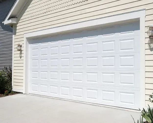 A white garage door is sitting on the side of a house.
