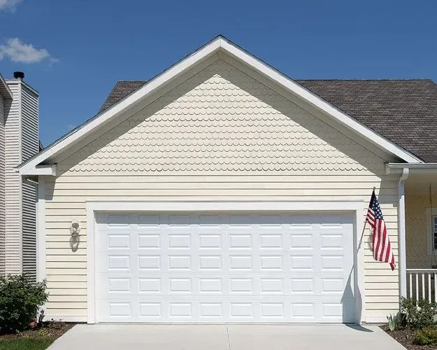 A house with a white garage door and an american flag