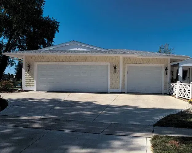 A large house with three garage doors and a driveway.