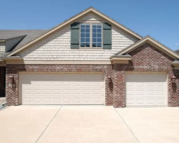A house with two garage doors and a window with green shutters