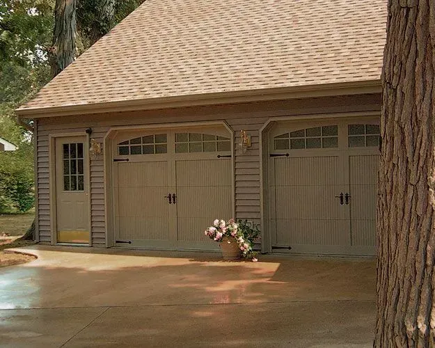A garage with two garage doors and a concrete driveway