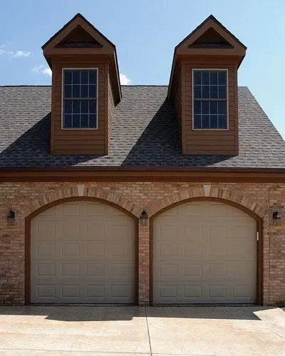 A house with two garage doors and two windows on the roof