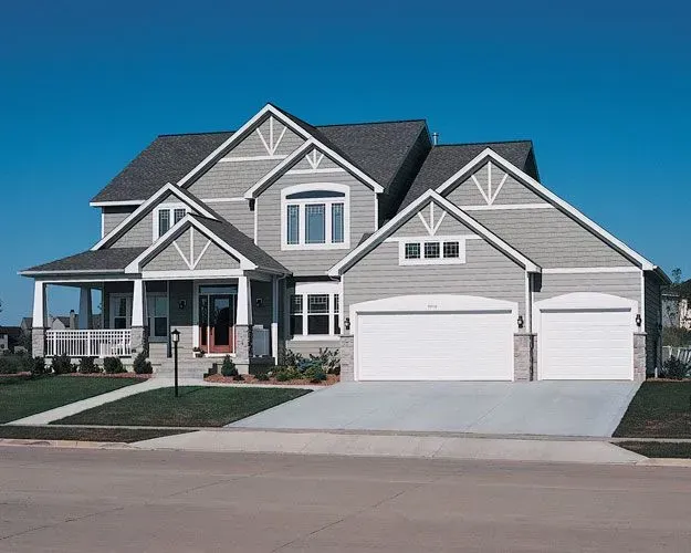 A large house with two garage doors and a concrete driveway