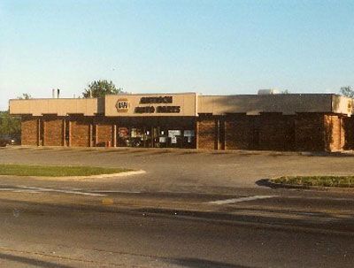 A brick NAPA Auto Parts store with a flat roof, viewed from across a paved parking lot on a clear day.