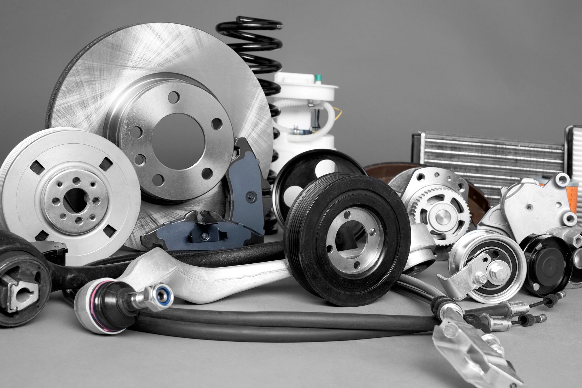 A collection of assorted metallic automotive spare parts, including brake rotors, a coil spring, and a suspension arm.