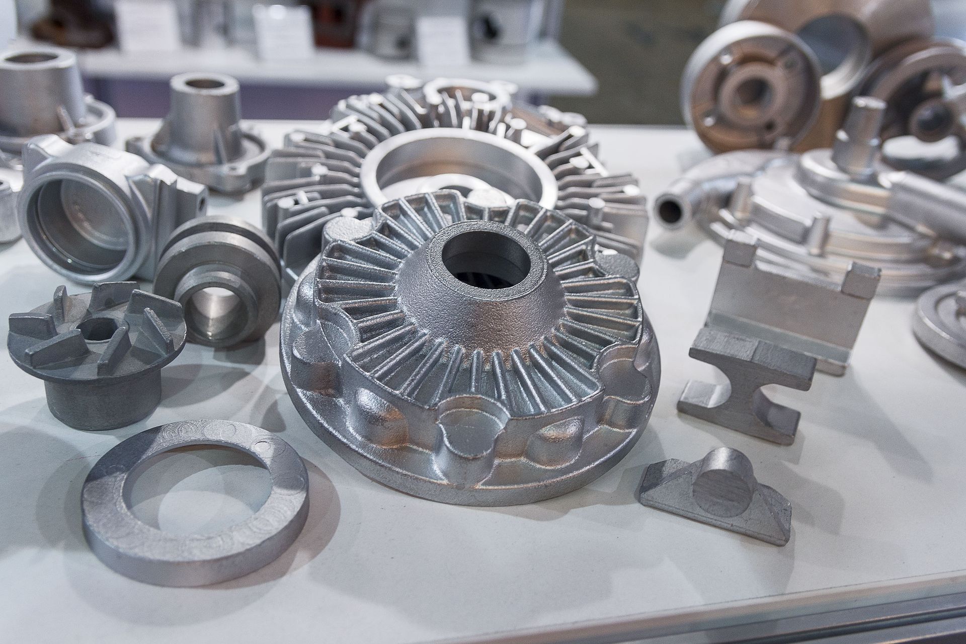 An assortment of raw, silver-toned metal mechanical parts and cast components displayed on a table.