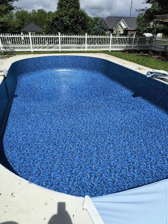 A large swimming pool with blue water and a white fence surrounding it.