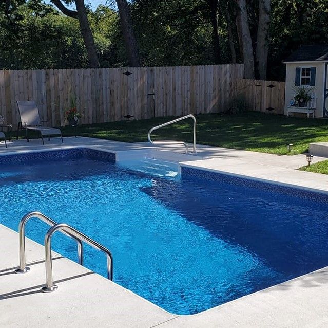 A large swimming pool with a wooden fence in the background