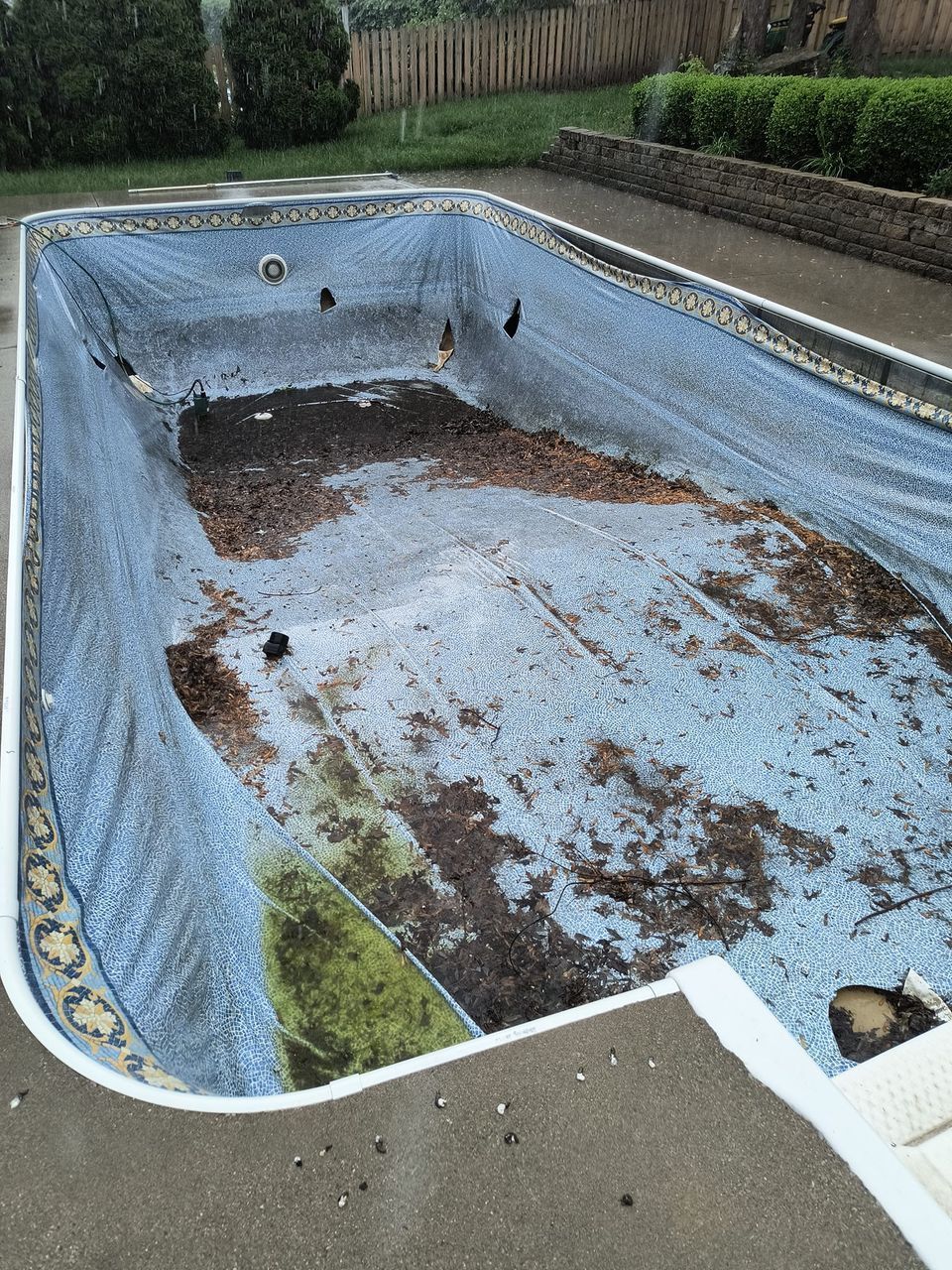An empty swimming pool with a blue tarp covering it.