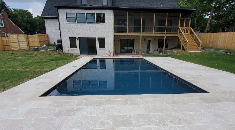 A large swimming pool is in the backyard of a house.