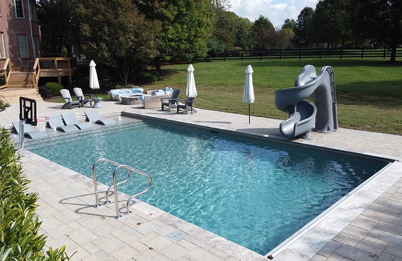 A large swimming pool with a slide in the backyard