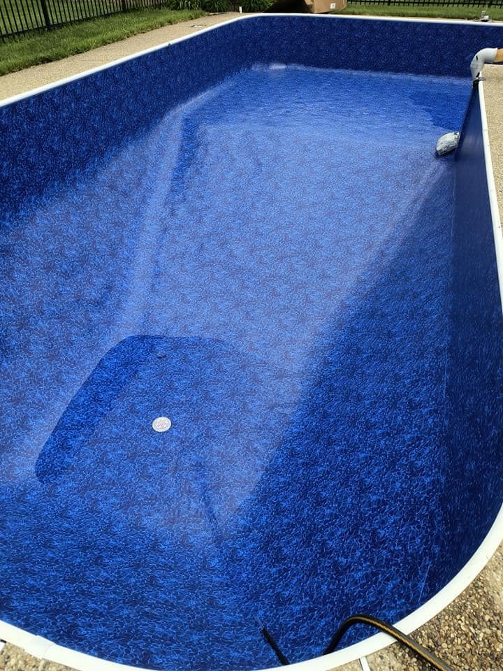 A large blue swimming pool is sitting on top of a concrete patio.