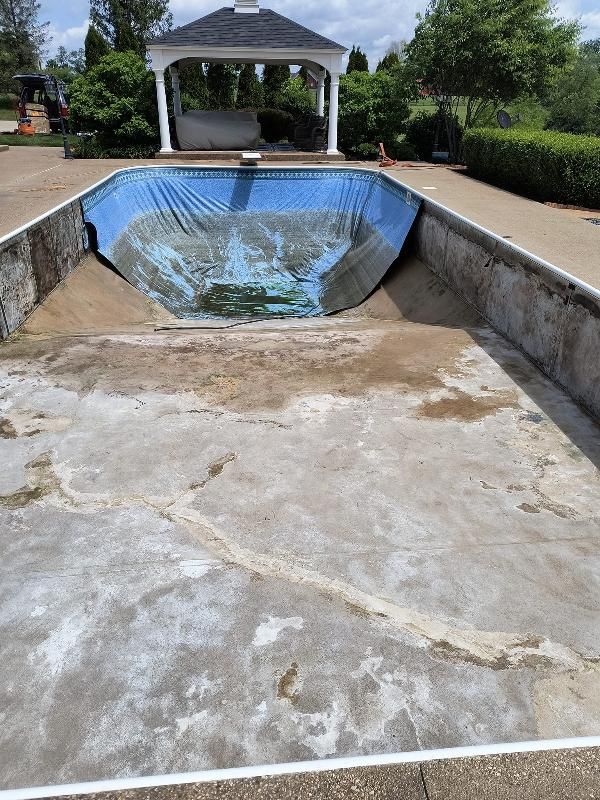 An empty swimming pool with a gazebo in the background.