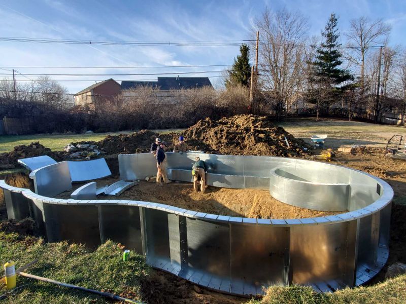 A large metal swimming pool is being built in a backyard.