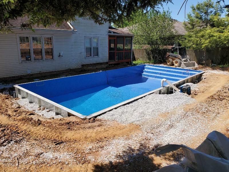 A large swimming pool is being built in the backyard of a house.