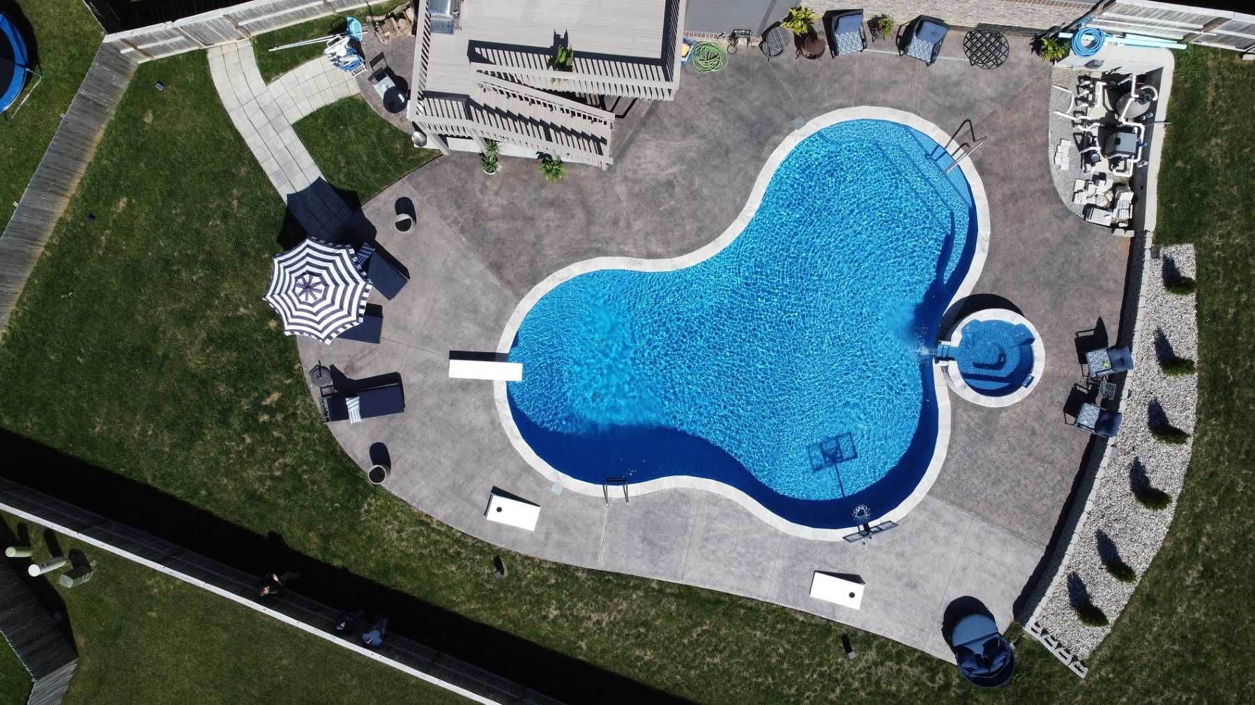 An aerial view of a large swimming pool surrounded by lawn chairs and umbrellas.