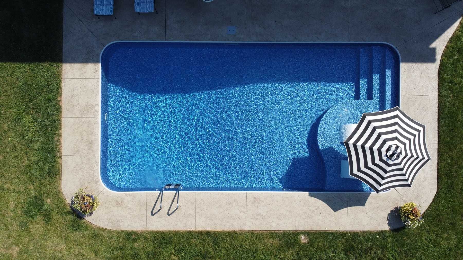 An aerial view of a swimming pool with a black and white umbrella.
