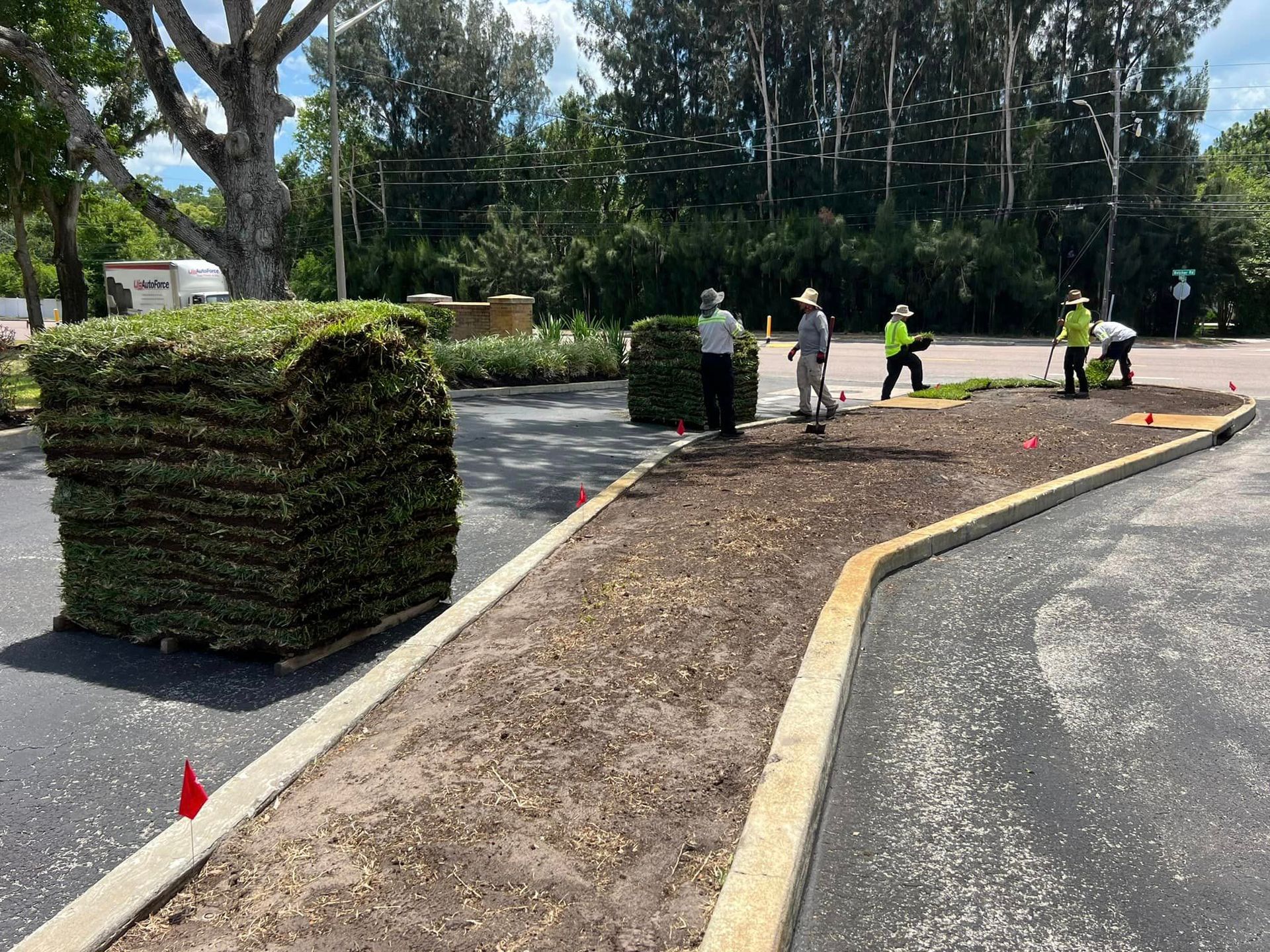 A group of people are working on a lawn in a parking lot.