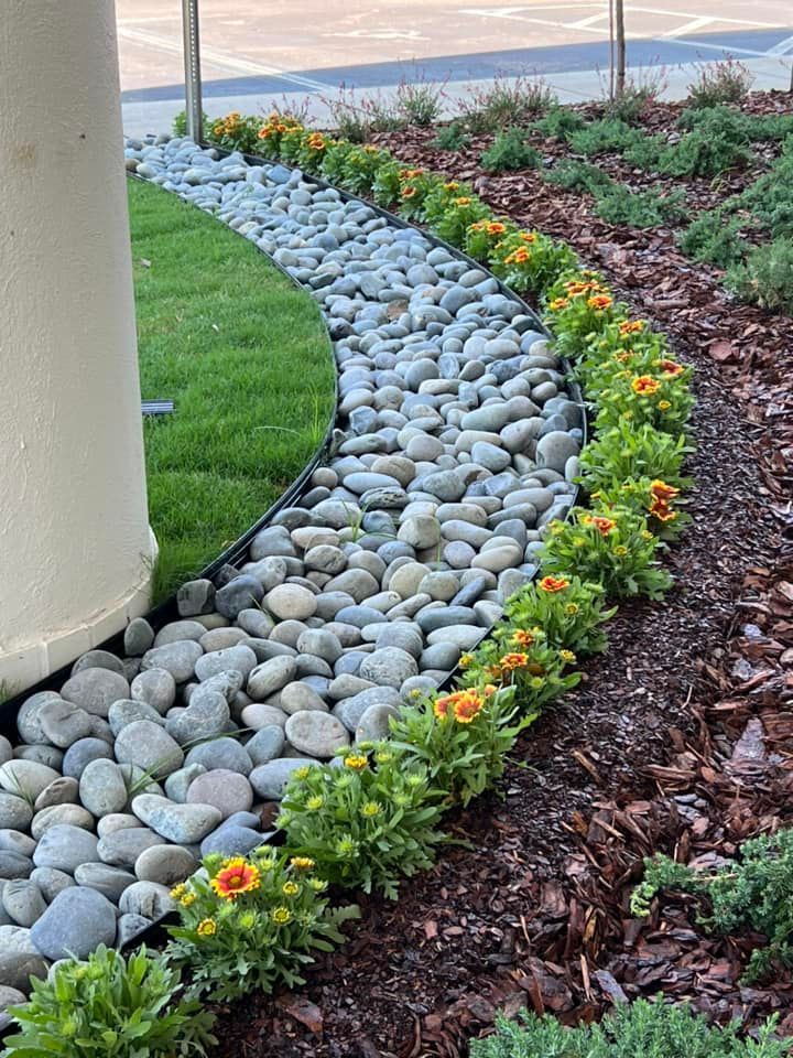 A garden filled with rocks , flowers and mulch.
