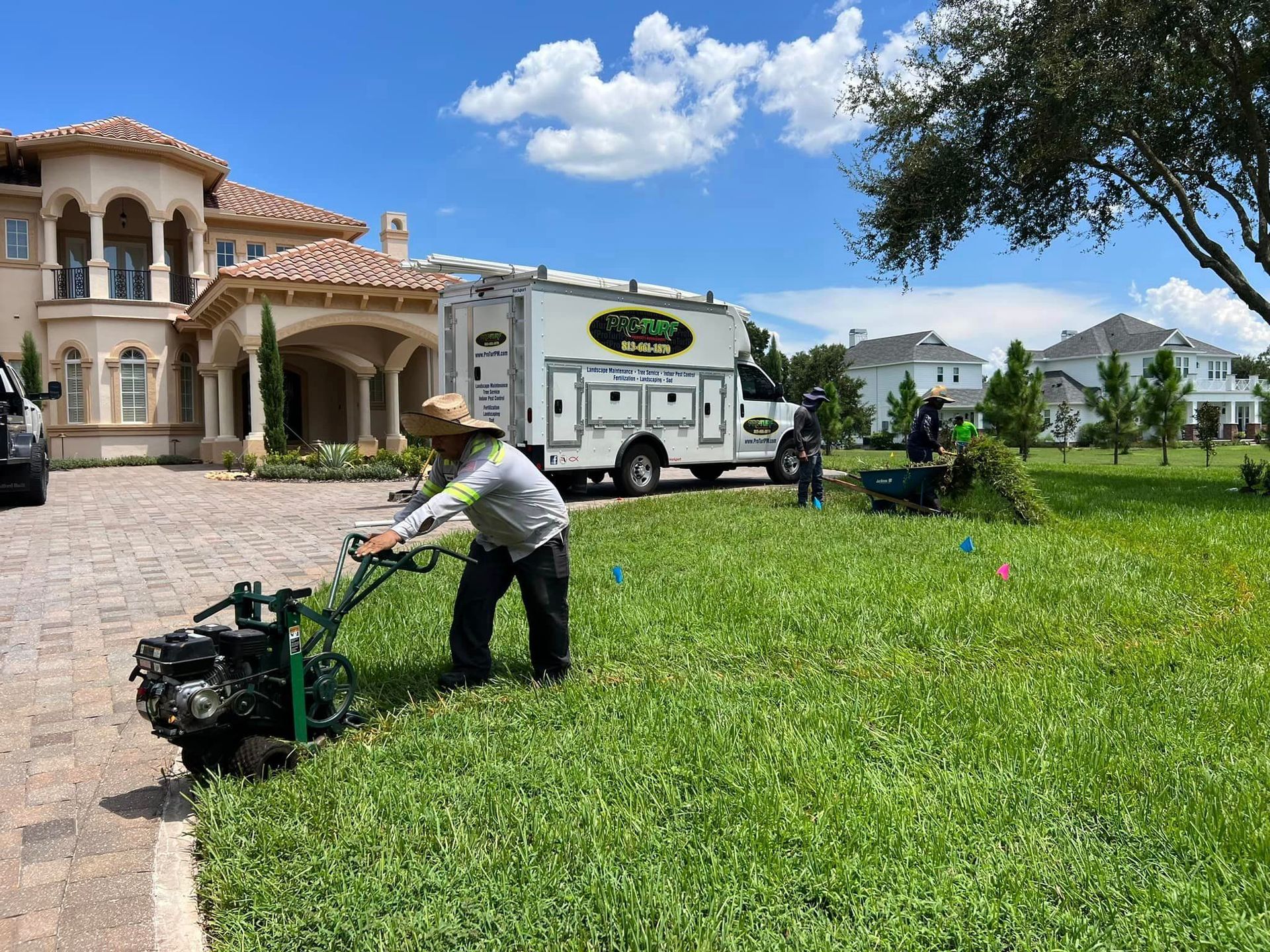 A man is using a lawn mower in front of a large house.