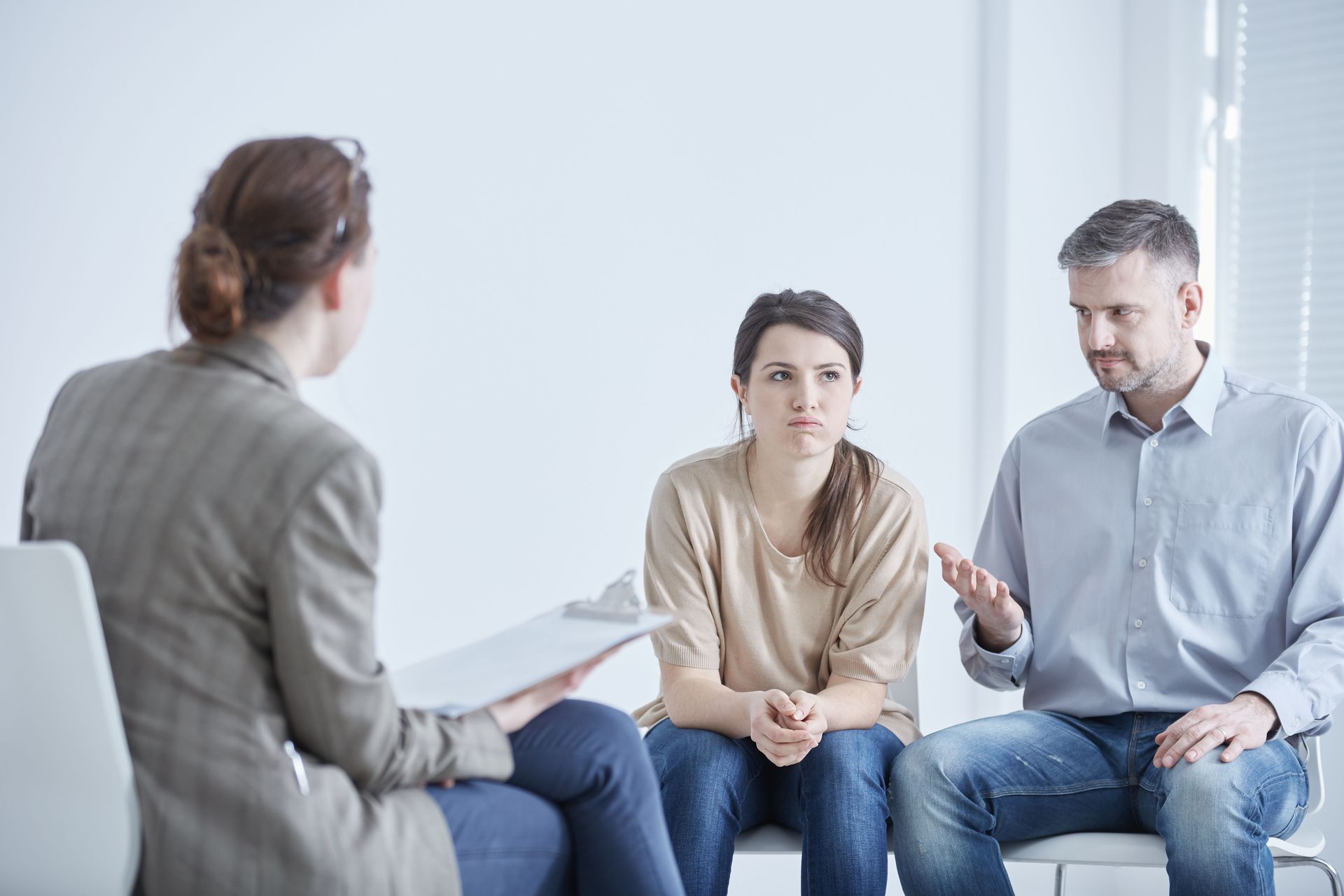 Therapist speaking with a seated couple in a bright counseling office