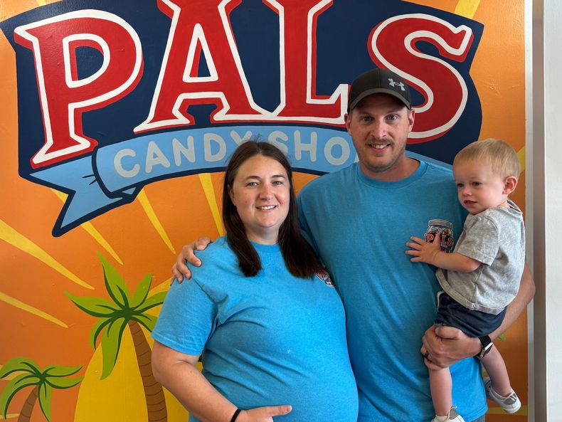 Family poses in front of the PALS CANDY SHOP sign.