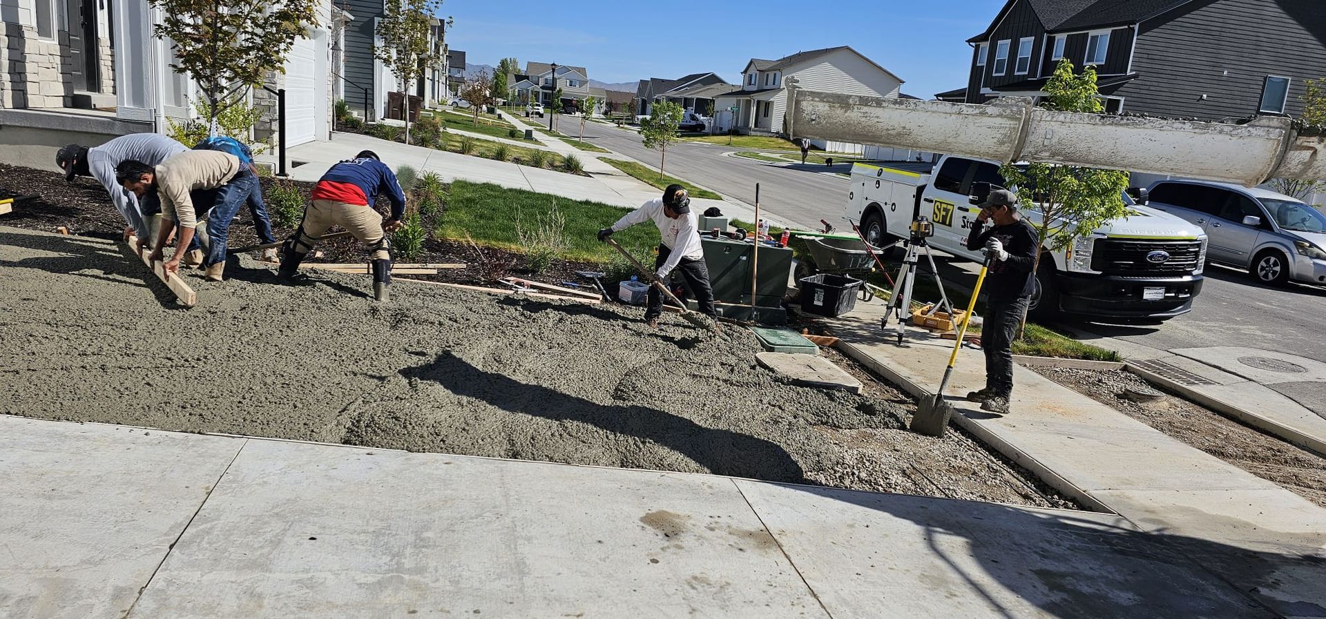 A group of construction workers are working on a sidewalk in a residential neighborhood.