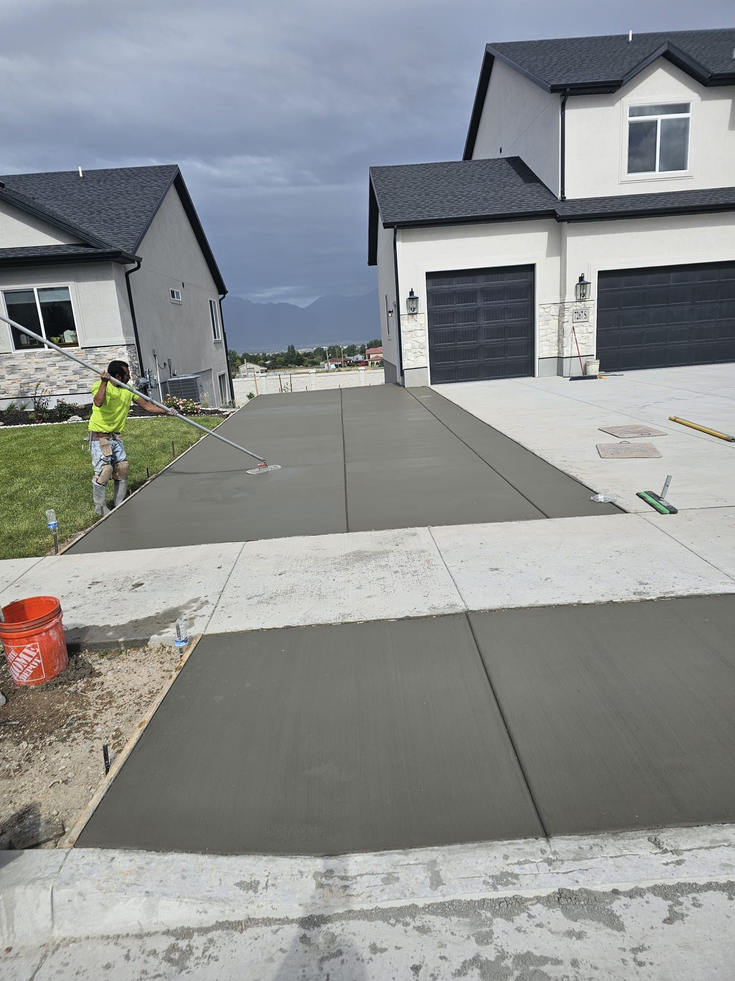 A man is working on a concrete driveway in front of a house.