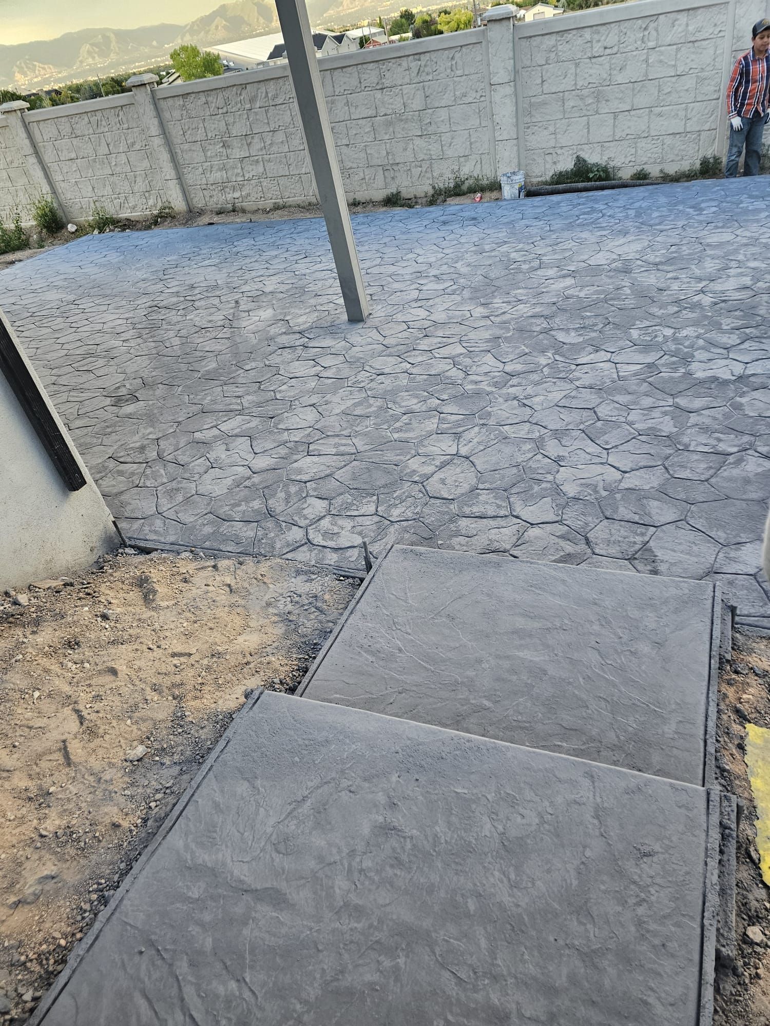 A concrete walkway with stairs leading up to a brick wall.