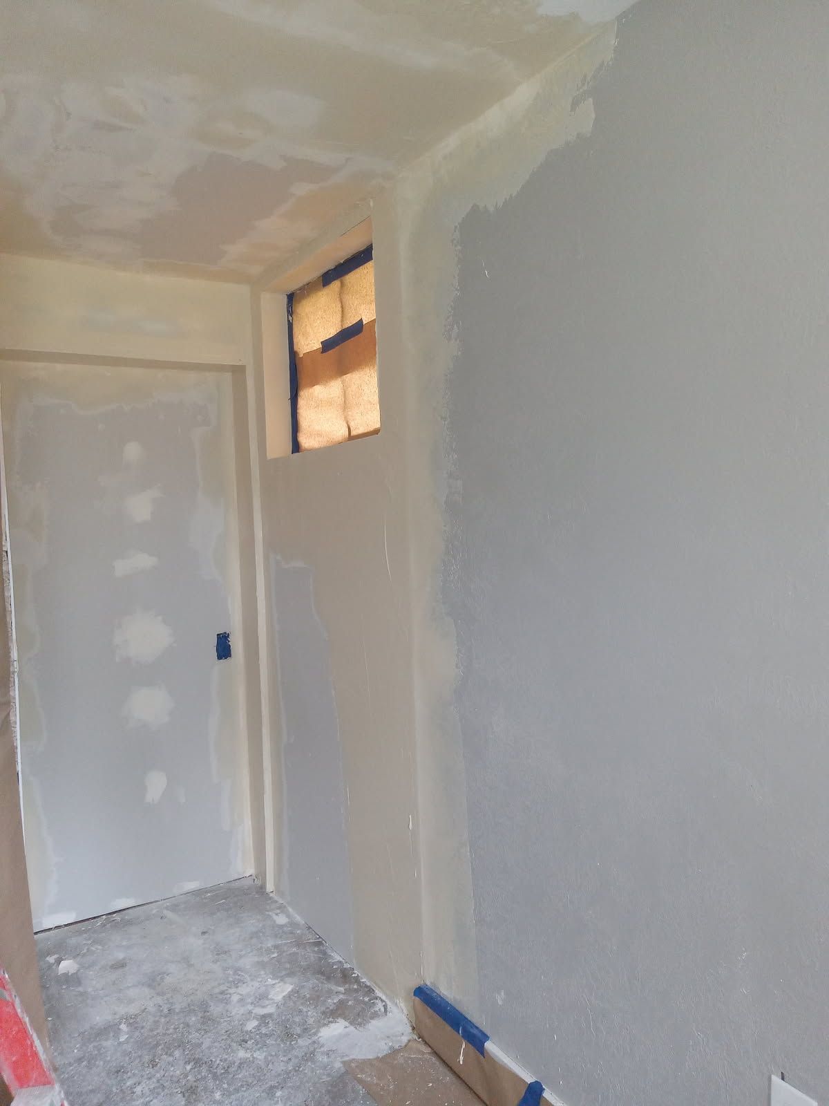 A hallway with a door and a window in a house under construction.