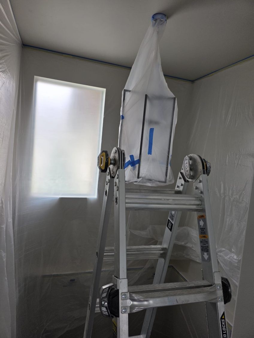 A ladder is sitting in a room covered in plastic.