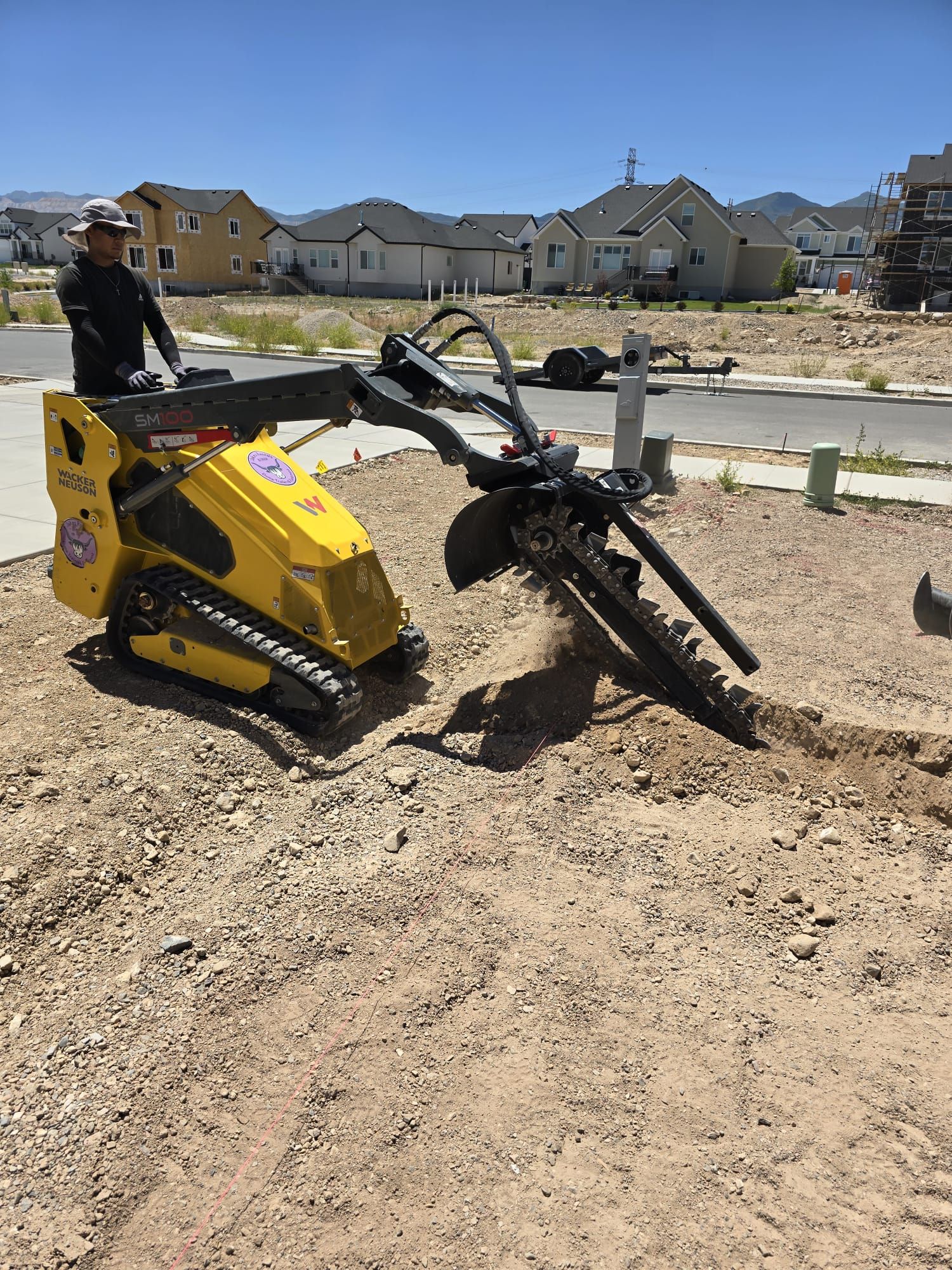 A man is standing next to a yellow machine in a dirt field.