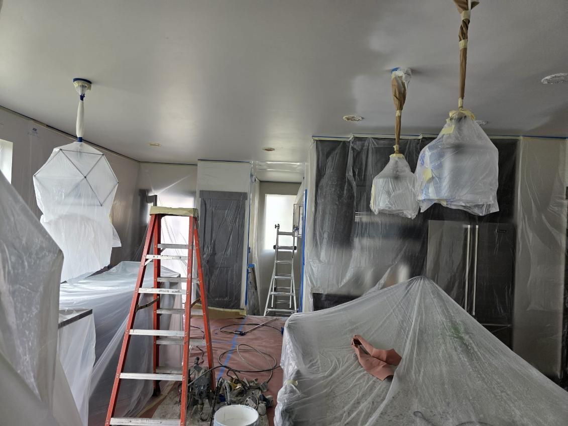 A kitchen is being painted and covered in plastic.