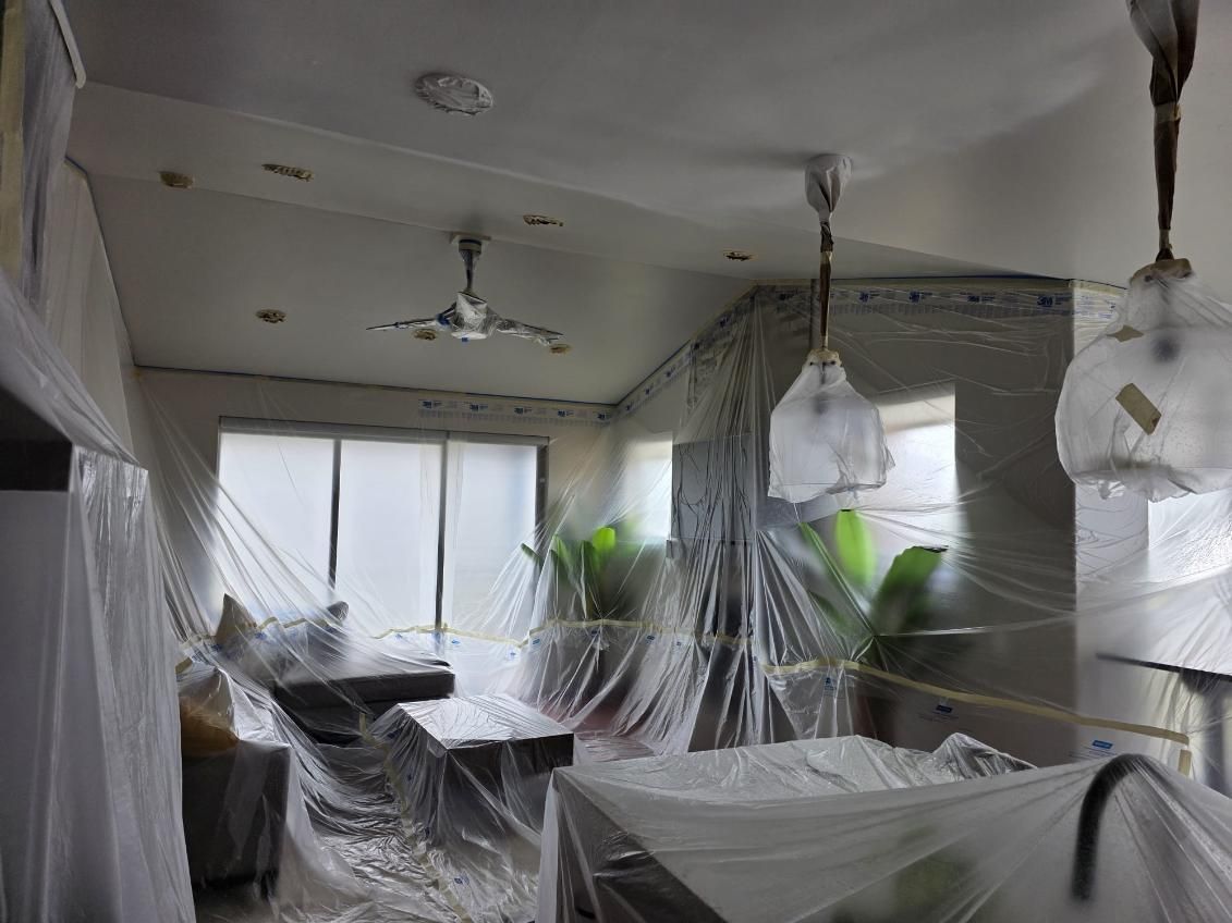 A living room covered in plastic wrap and a ceiling fan.